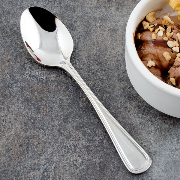 A Walco stainless steel dessert spoon next to a bowl of chocolate ice cream.