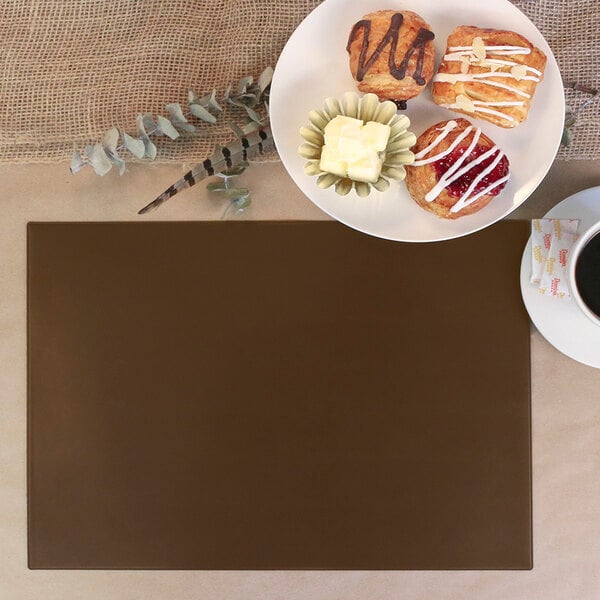 A brown rectangular vinyl placemat on a table with a plate of pastries and a cup of coffee.