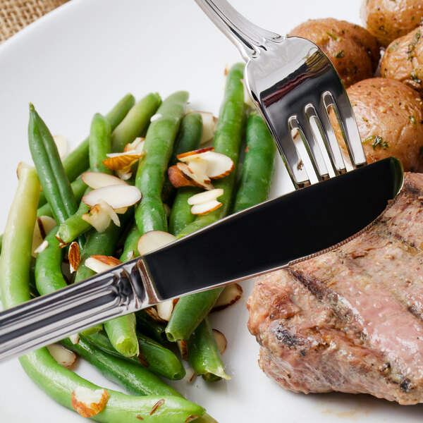 A plate of food with a Walco stainless steel dinner knife and fork.