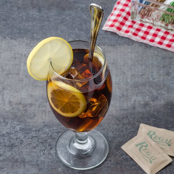 A glass of iced tea with a Walco stainless steel iced tea spoon and lemon slices.