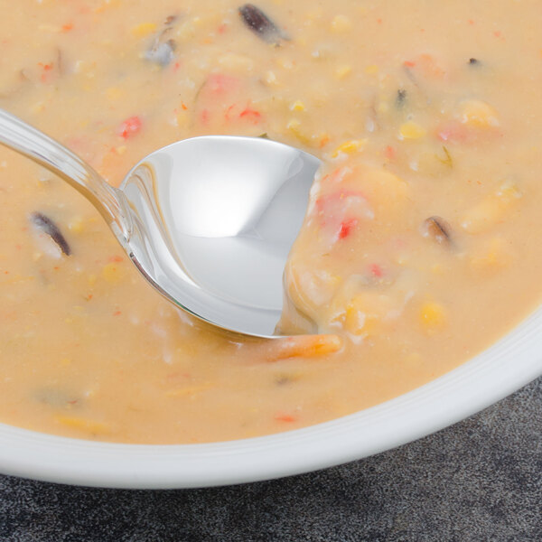 A Walco stainless steel bouillon spoon in a bowl of soup.