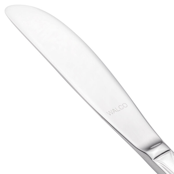 A close-up of a silver Walco Prim butter knife with a white surface.