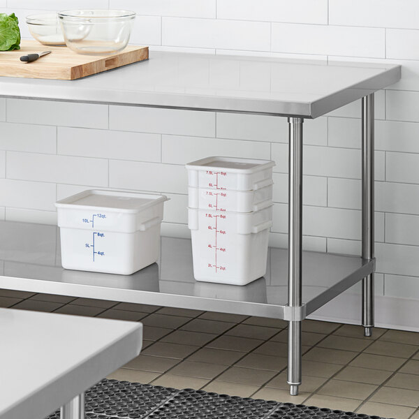 A Regency stainless steel work table undershelf with metal poles holding white plastic containers.