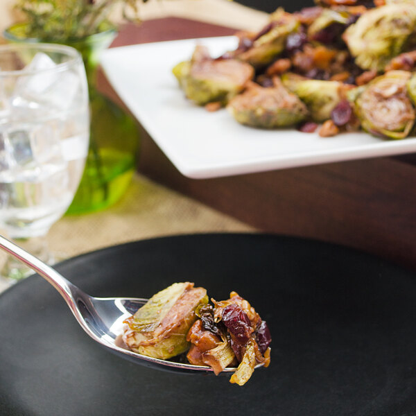 A Walco Freya stainless steel serving spoon with food on it.