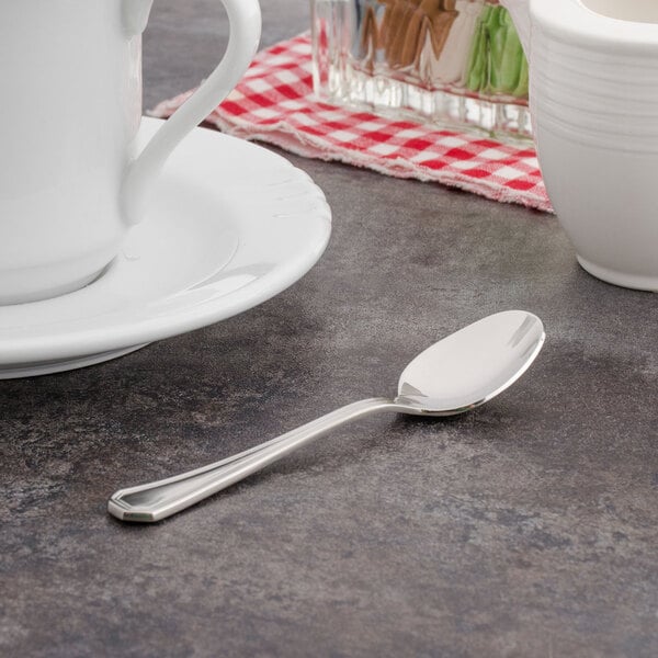 A Walco stainless steel demitasse spoon in a white cup on a saucer.