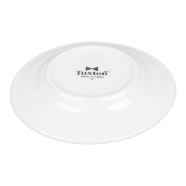 A small, bright white china plate with a wide rim and rolled edge, shown upside down with the Tuxton brand mark visible.