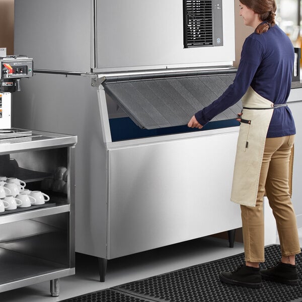 A woman in an apron opening a Hoshizaki ice storage bin.