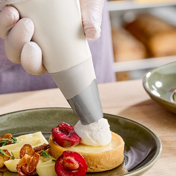 A hand using an Ateco plain piping tip on a dessert.
