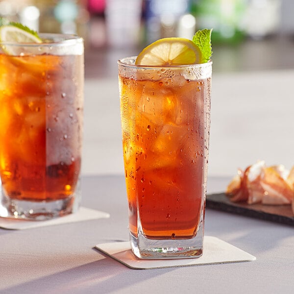 Two Acopa Cube beverage glasses filled with iced tea, lemon slices, and mint leaves.