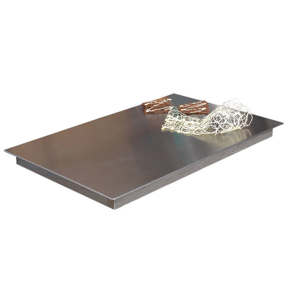 A Matfer Bourgeat cold plate on a metal surface with brown pastries on a net.