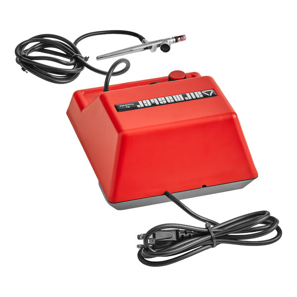 A red airbrush compressor unit with attached airbrush tool and power cord, shown on a white background.