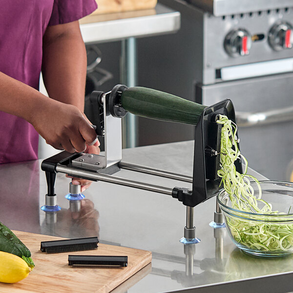 A manual spiral vegetable slicer being used to create vegetable noodles from a zucchini.