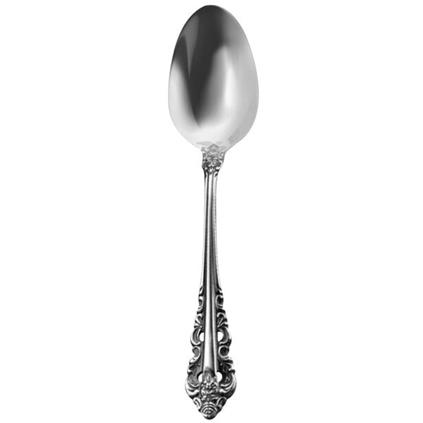 A close-up of a Walco stainless steel dessert spoon with an ornate design.