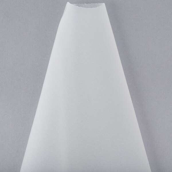 A white cone shaped pastry bag on a gray surface.