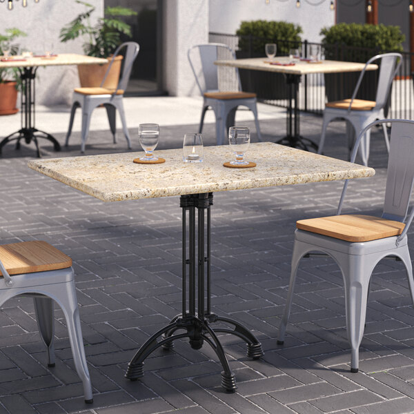 A table with a Art Marble Furniture Kashmir White Granite Tabletop and chairs on a patio.