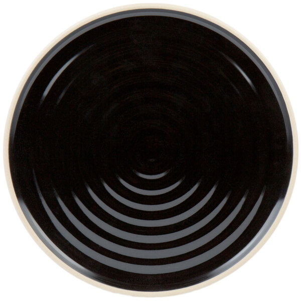 A black Chef & Sommelier dinner plate with a white rim with a spiral design.