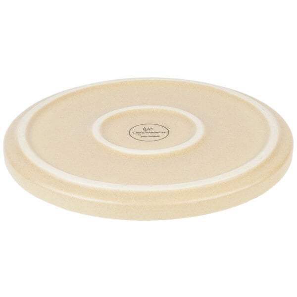 A white stoneware plate with a circular design on the rim.