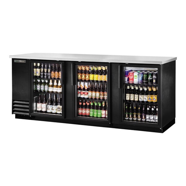 A black True back bar refrigerator full of beer bottles.