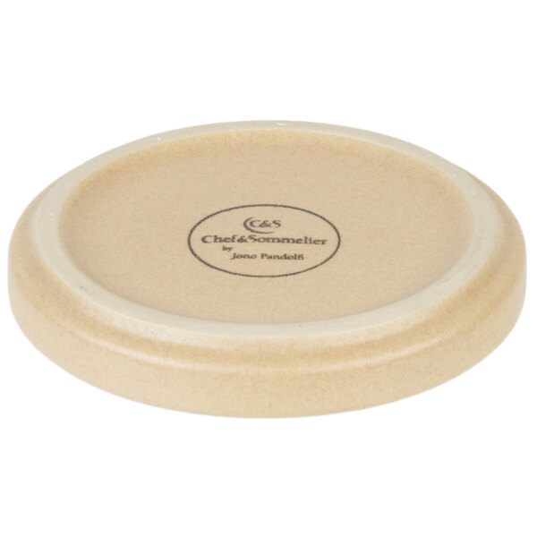 A white stoneware plate with a black circular logo.