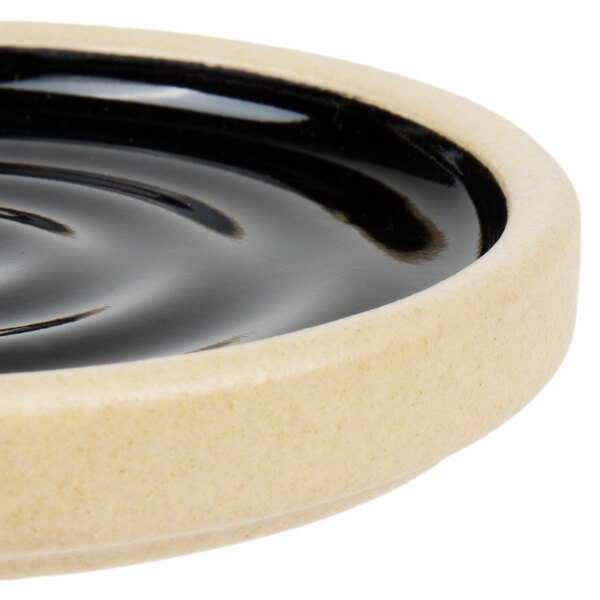 A close up of a black ceramic Chef & Sommelier Geode plate with a wavy surface.