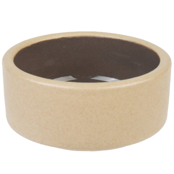 A beige stoneware ramekin with a brown rim.