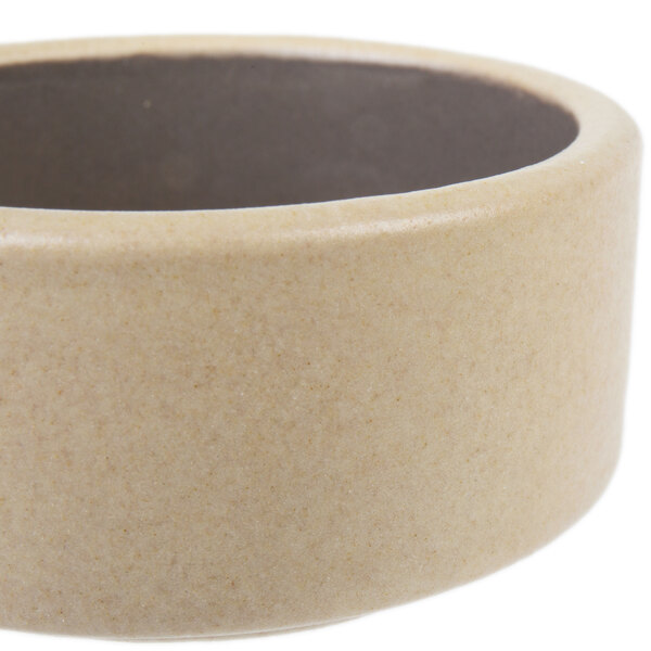 A beige stoneware ramekin with a black rim.