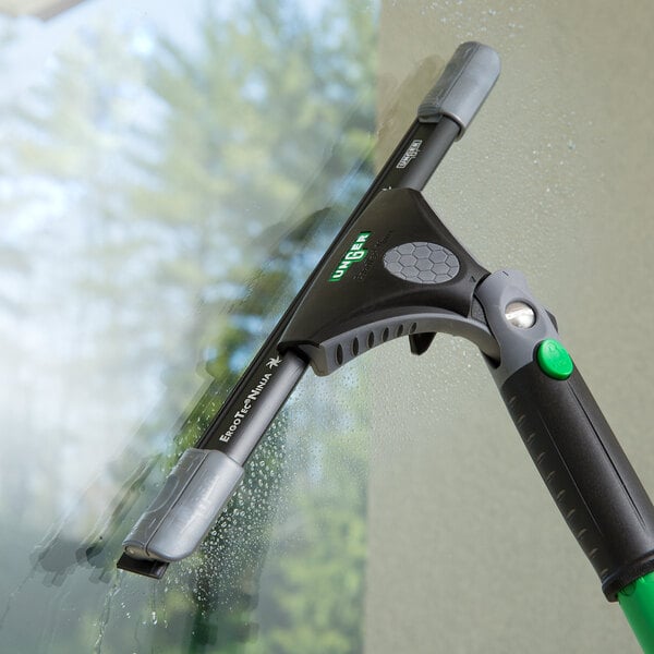 A green and black Unger ErgoTec Ninja squeegee cleaning a window.