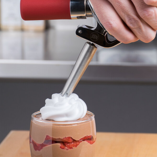 A person using iSi stainless steel decorator tips to make a dessert.