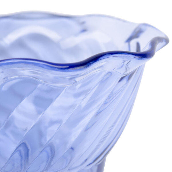 A close up of a transparent blue tulip dessert dish with a wavy design.