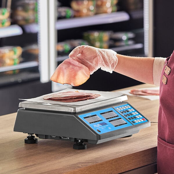 A woman weighing meat on an AvaWeigh digital price computing scale on a deli counter.