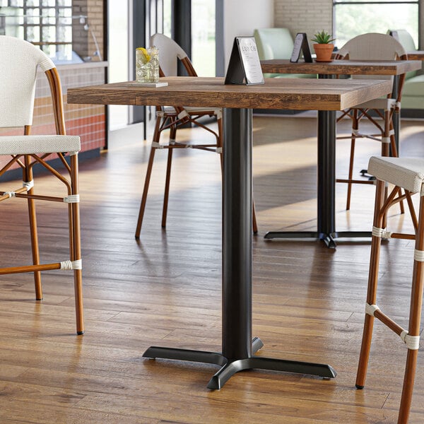 A Lancaster Table & Seating black bar height column table base on a wooden table in a restaurant.