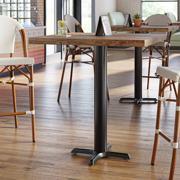 A Lancaster Table & Seating black cast iron bar height table base on a table in a restaurant dining area.
