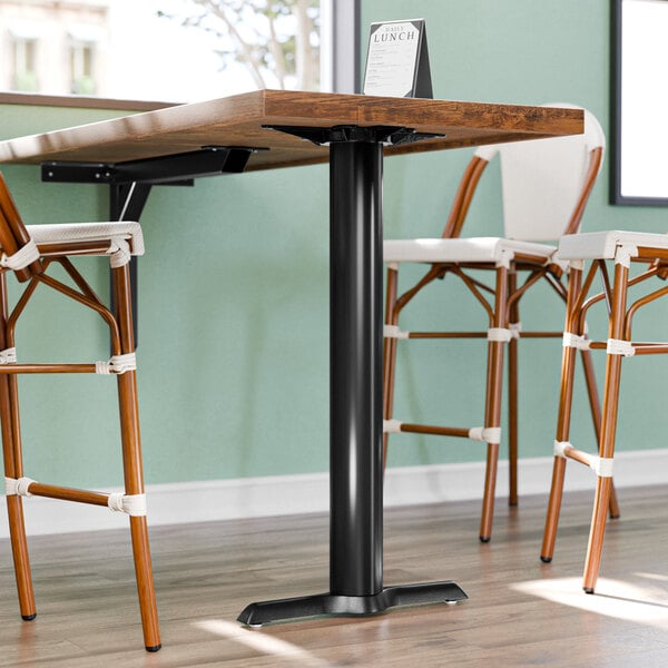 A Lancaster Table & Seating cast iron bar height end table base with chairs around it.