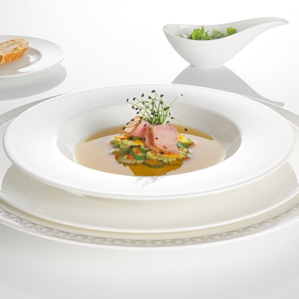 A Villeroy & Boch white bone porcelain deep plate with soup and bread on it.