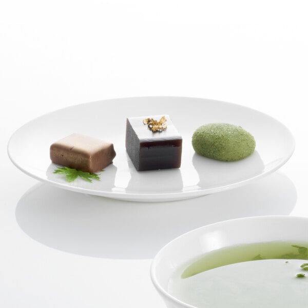 A Villeroy & Boch white bone porcelain plate with a bowl of food and a green tea cup on a white surface.