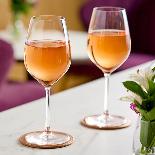 Two Chef & Sommelier Sequence wine glasses filled with wine on a table with flowers.