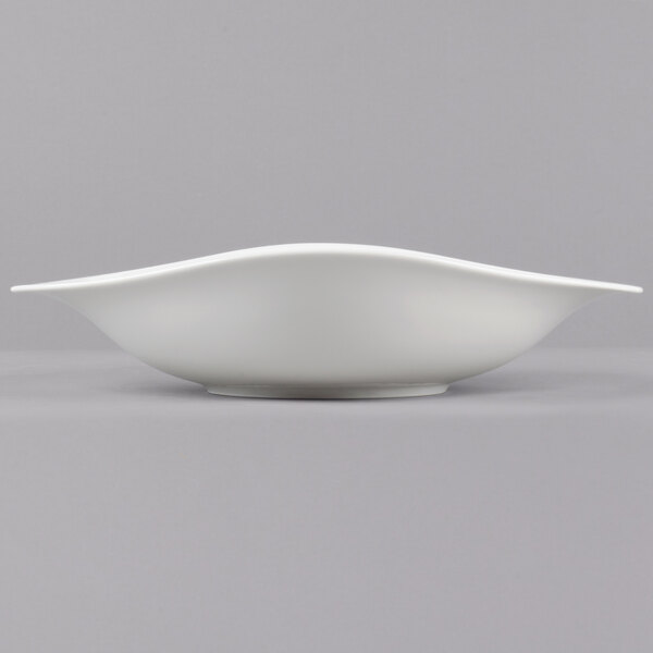 A Villeroy & Boch Dune white porcelain deep bowl with a curved edge on a gray background.