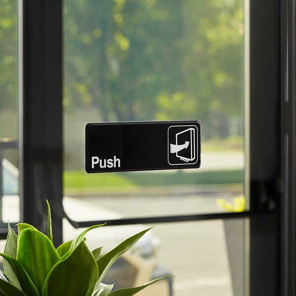 A black and white Thunder Group Push sign on a door.