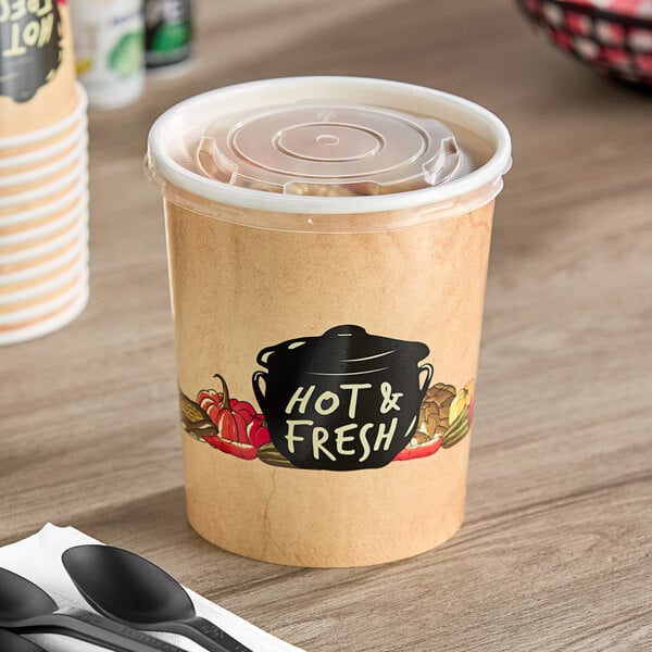 A Choice paper soup cup filled with food and covered with a vented plastic lid on a table.
