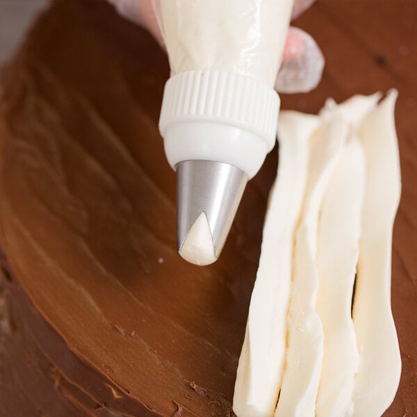 A person using an Ateco St. Honore piping tip on a pastry bag to decorate a cake.