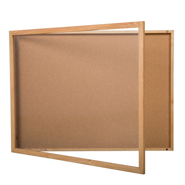 A wooden Aarco enclosed bulletin board with a cork interior and a glass door.