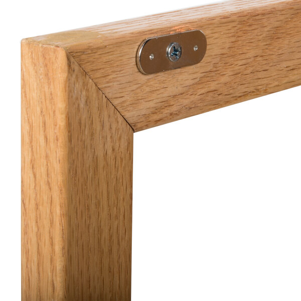 A close up of the natural oak wood frame of an Aarco enclosed display case with a metal latch.