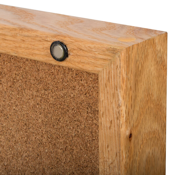 A close up of a wooden cork board with a metal button.