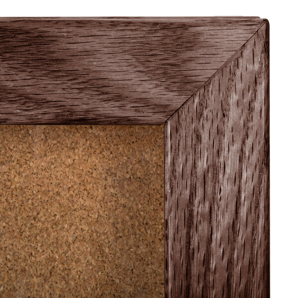 An Aarco walnut enclosed cork board on a table.