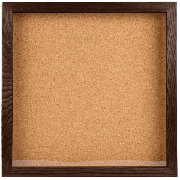 A cork board in a wooden frame with a walnut finish.