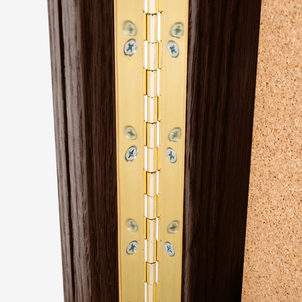 A close up of a brass hinge on a walnut door.