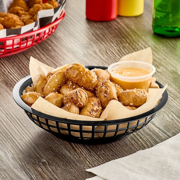 A Choice black plastic fast food basket filled with fries and dipping sauce.