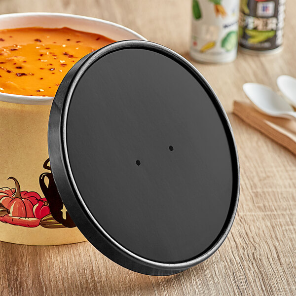 A black Choice paper soup container with a black lid on a table.