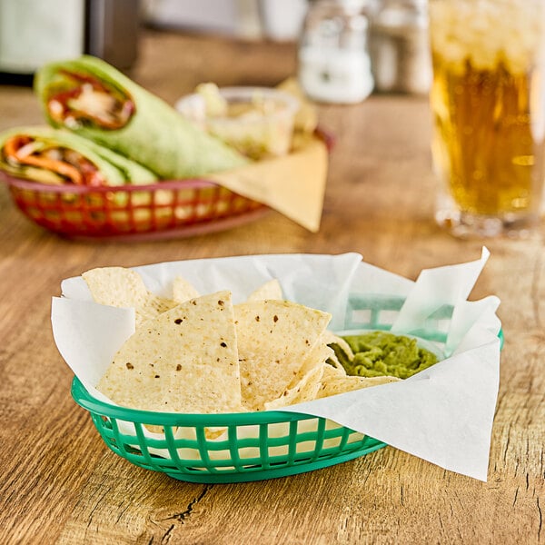 A green oval plastic fast food basket filled with chips on a table.