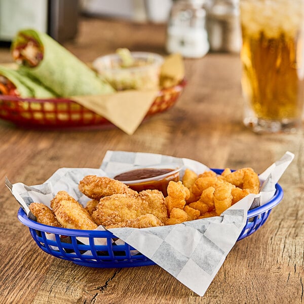 A Choice blue plastic oval fast food basket on a table with fried chicken strips.